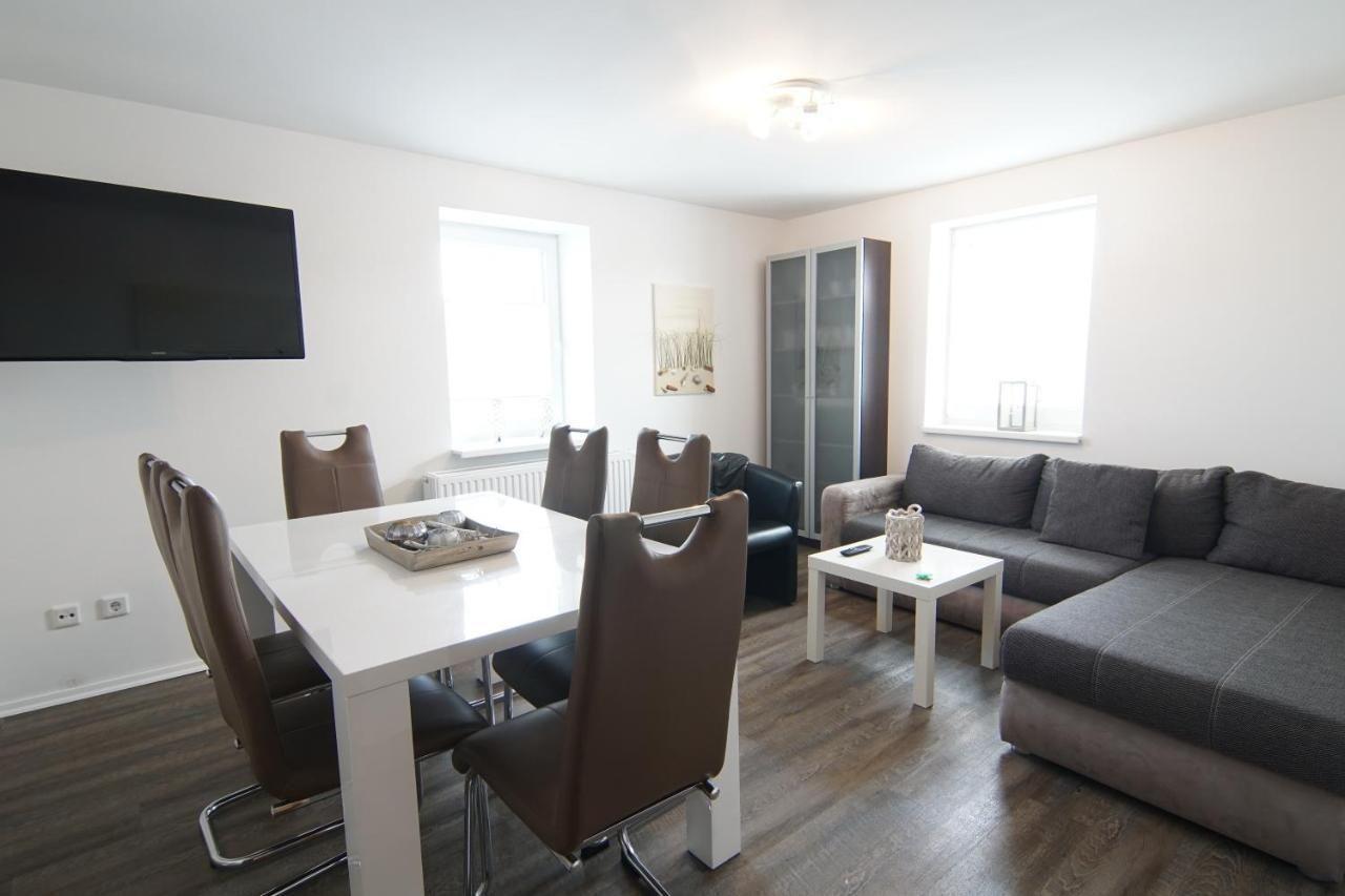 Wohn- und Essbereich mit Sofa, Esstisch und Fernseher an der Wand.
