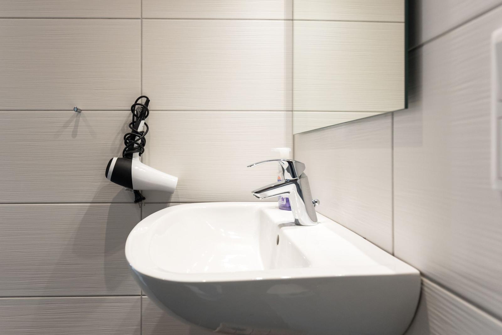 Waschbecken mit Wasserhahn und Haartrockner an der Wand
