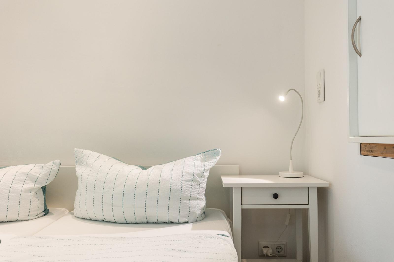 Ein Bett mit Kissen und Nachttisch mit Lampe.