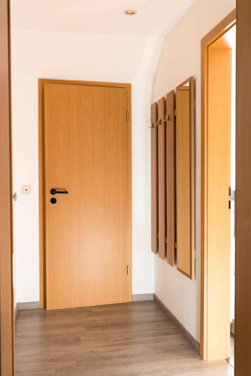 Flur mit Holztür und Spiegeln an der Wand.