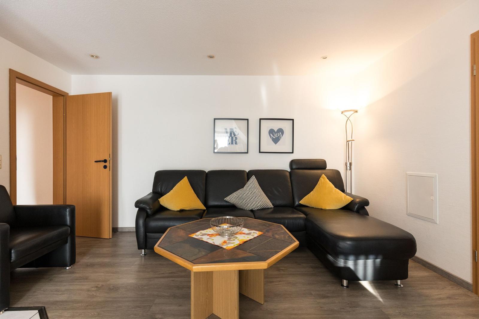 Schwarzes Sofa mit gelben und karierten Kissen, Holztisch und Stehlampe im Wohnzimmer.