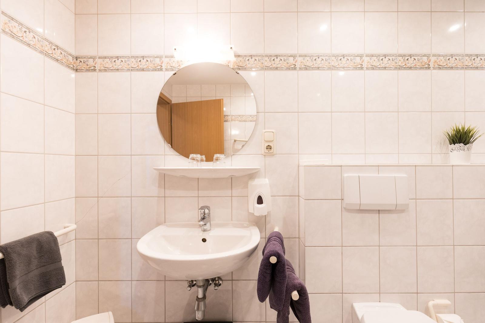 Badezimmer mit Waschbecken, Spiegel und Handtuchhalter