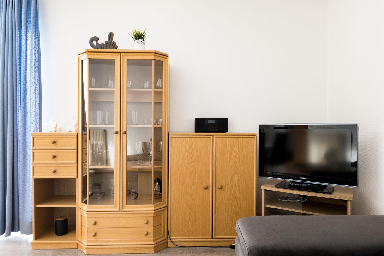 Holzschrank mit Glasfront, Fernseher und Sideboard im Wohnzimmer