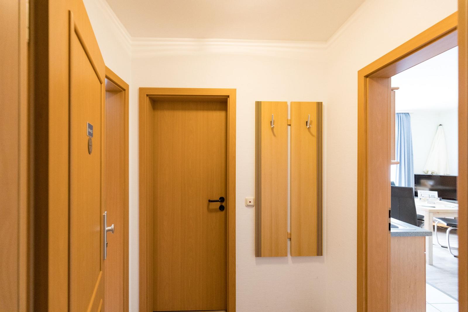 Flur mit Holztüren und Kleiderhaken an der Wand.