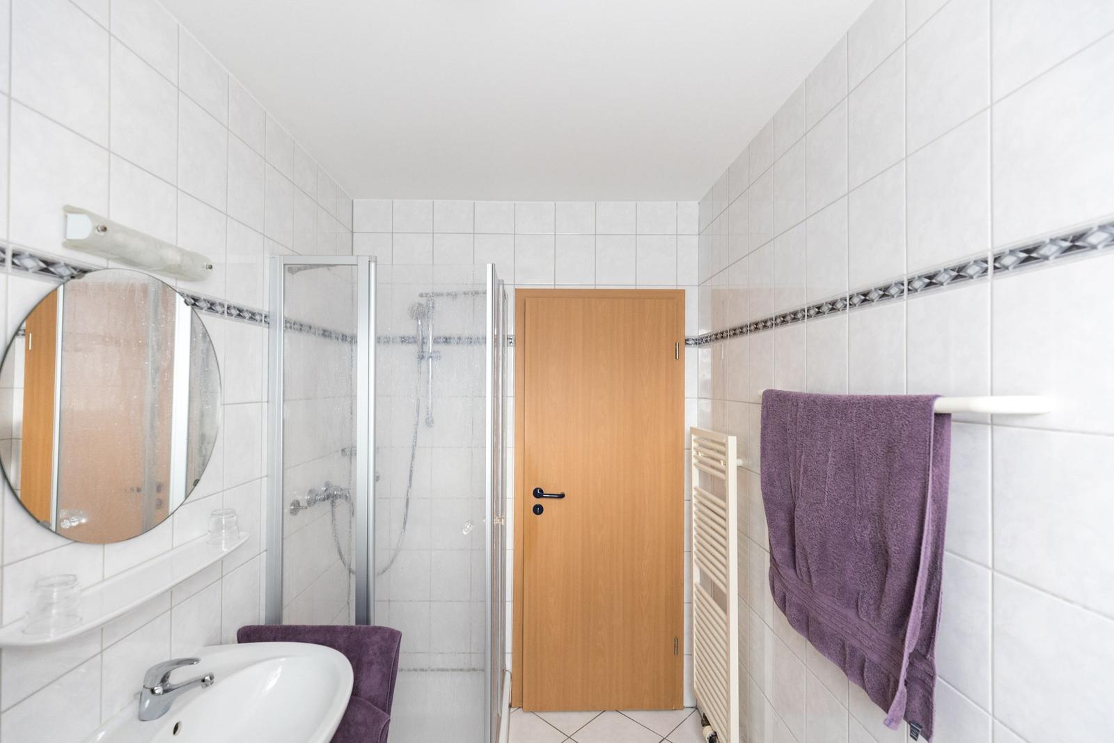 Badezimmer mit Dusche, Waschbecken und Handtuchhalter.