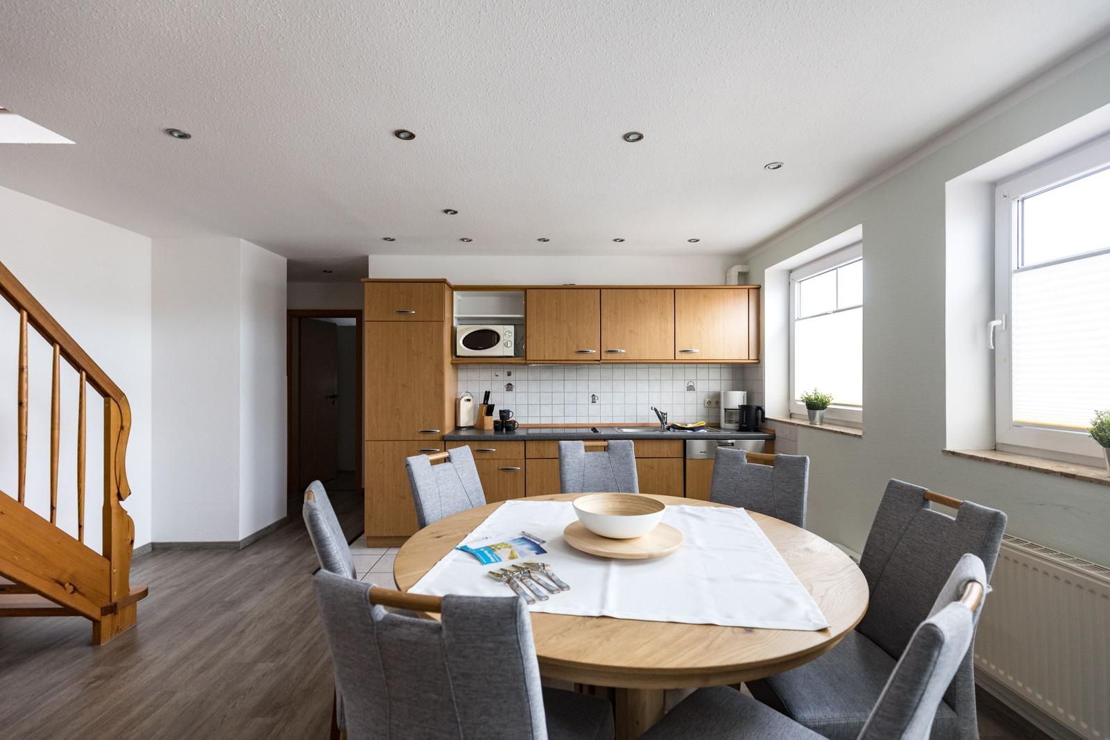 Essbereich mit runder Tisch und Stühlen, Küche mit Holzschränken und Fenster