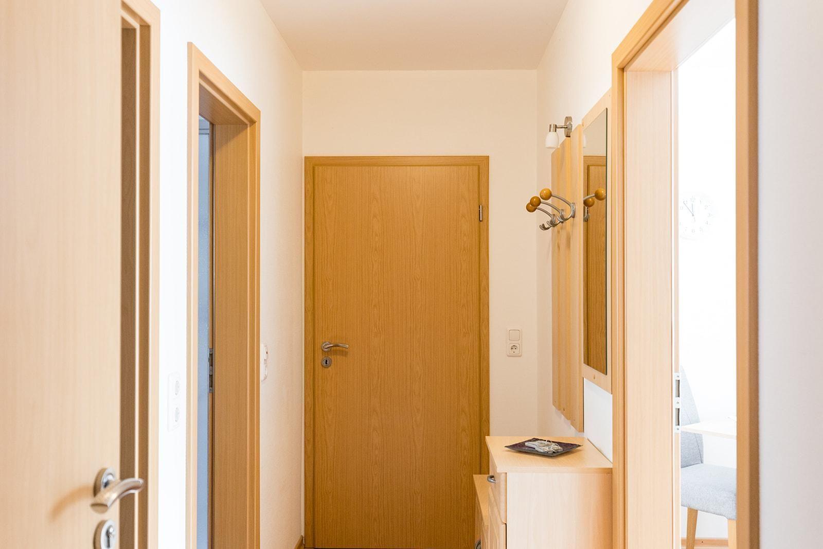 Flur mit Holztüren, Spiegelschrank und Haken für Kleidung.