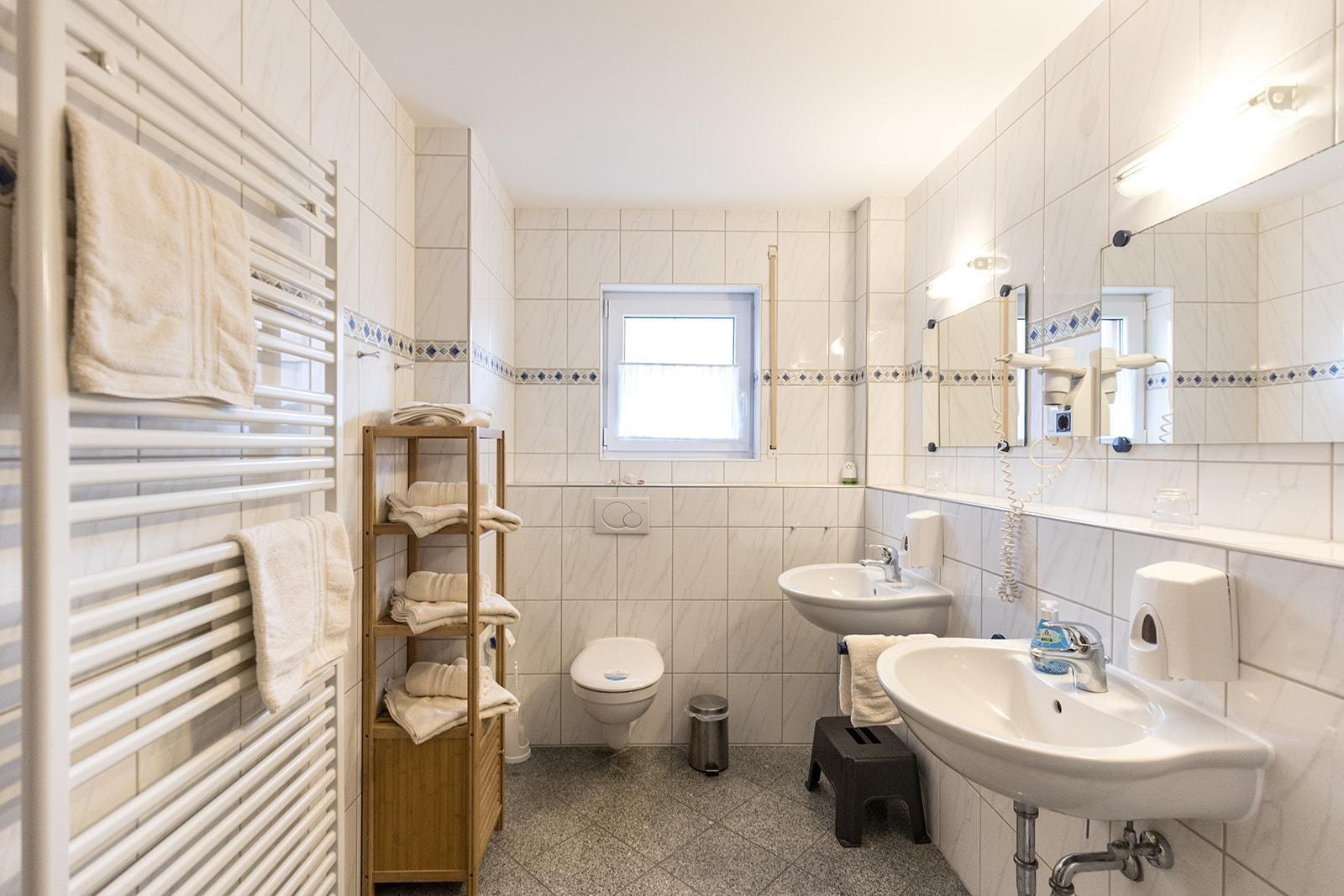 Badezimmer mit Toilette, Waschbecken und Heizkörper. Handtücher aufgestellt.