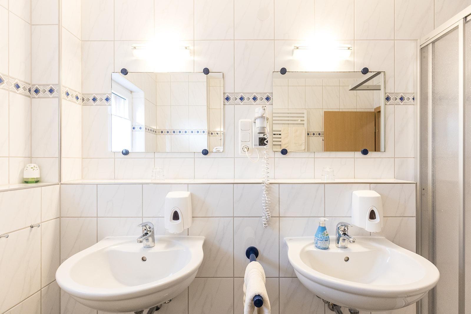 Zwei Waschbecken mit Spiegeln und Handtuchhalter an der Wand.
