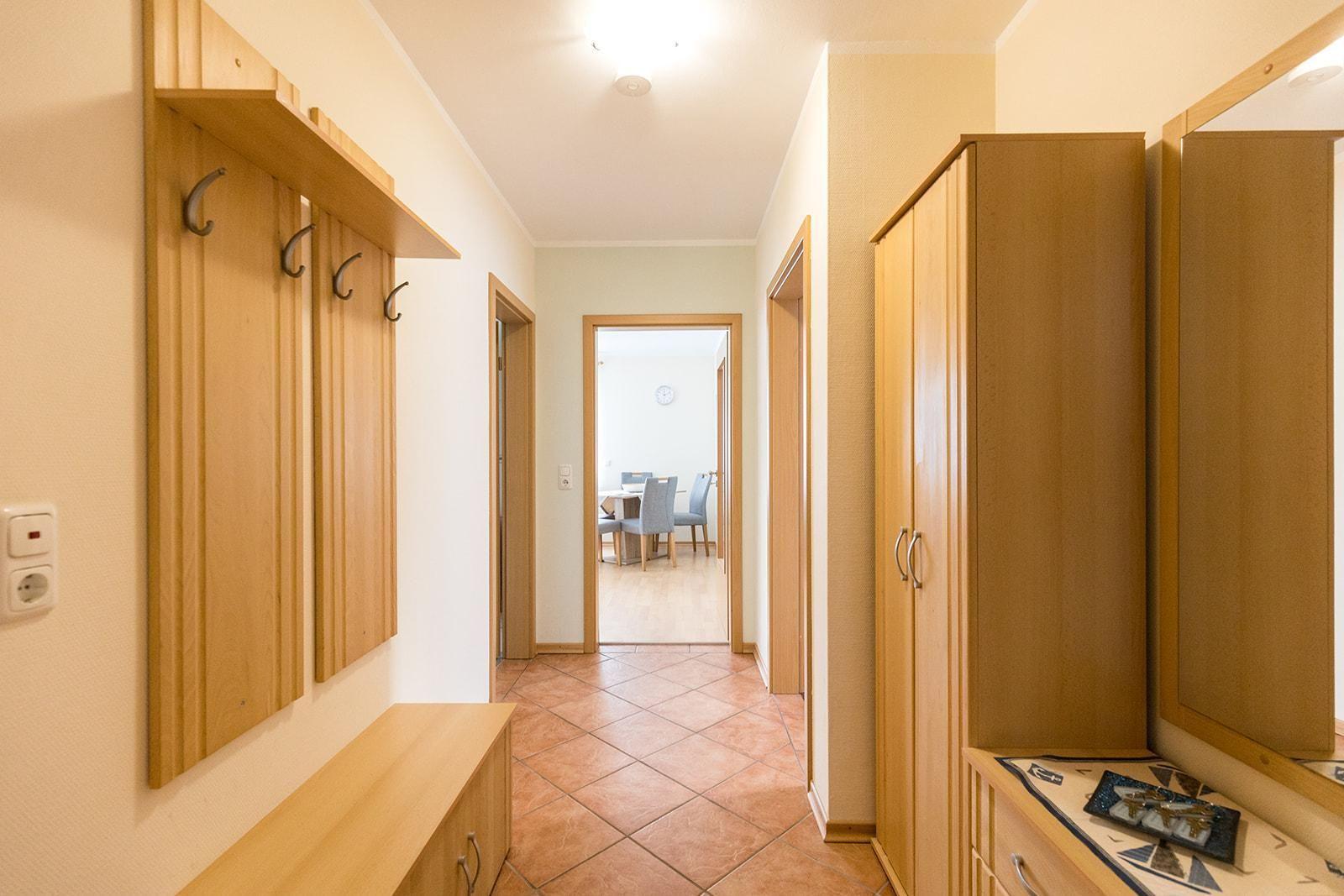 Flur mit Holzgarderobe, Schrank und Blick in Esszimmer.