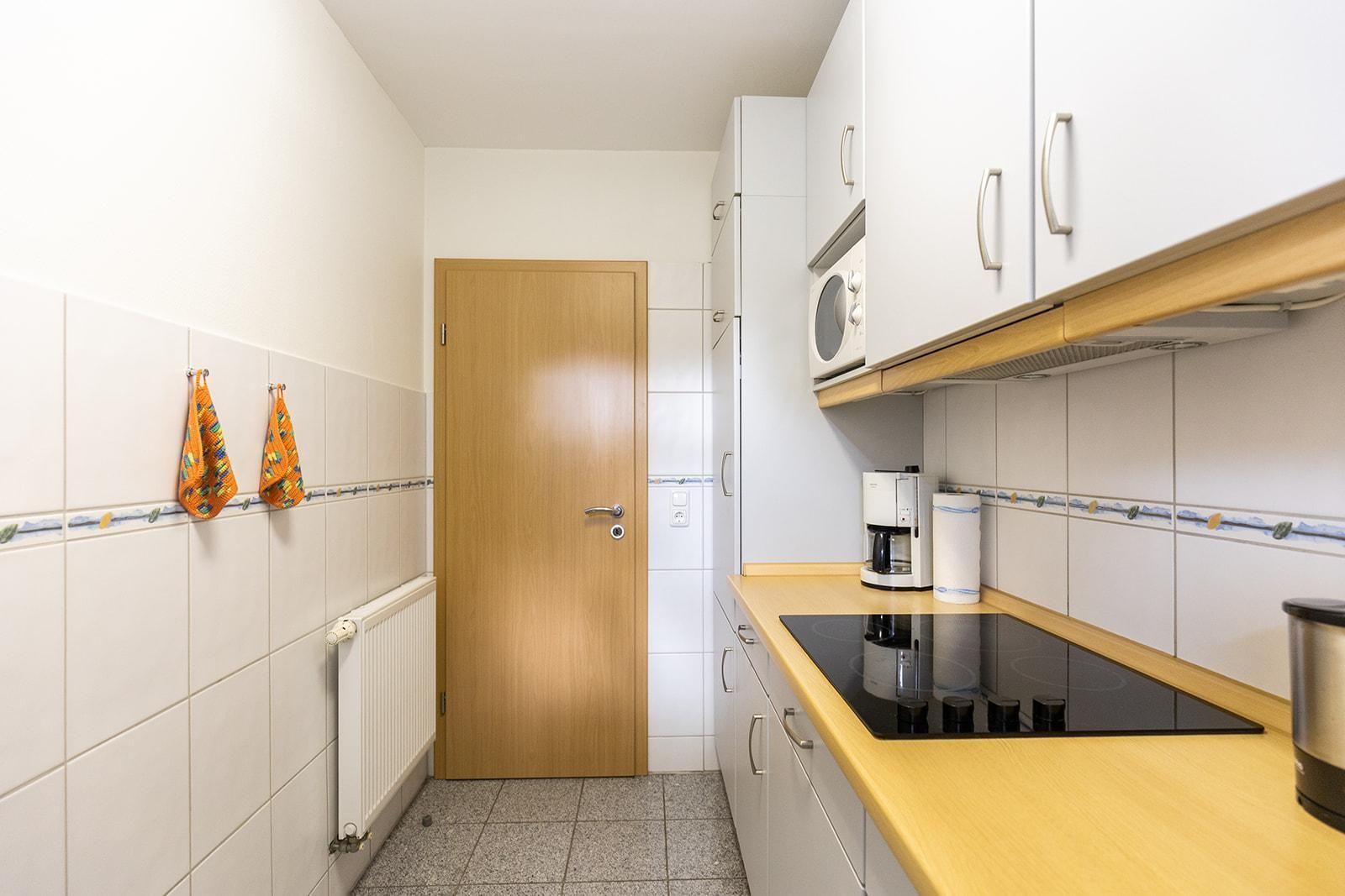 Kitchen with white cabinets, wooden countertop, and induction cooktop.