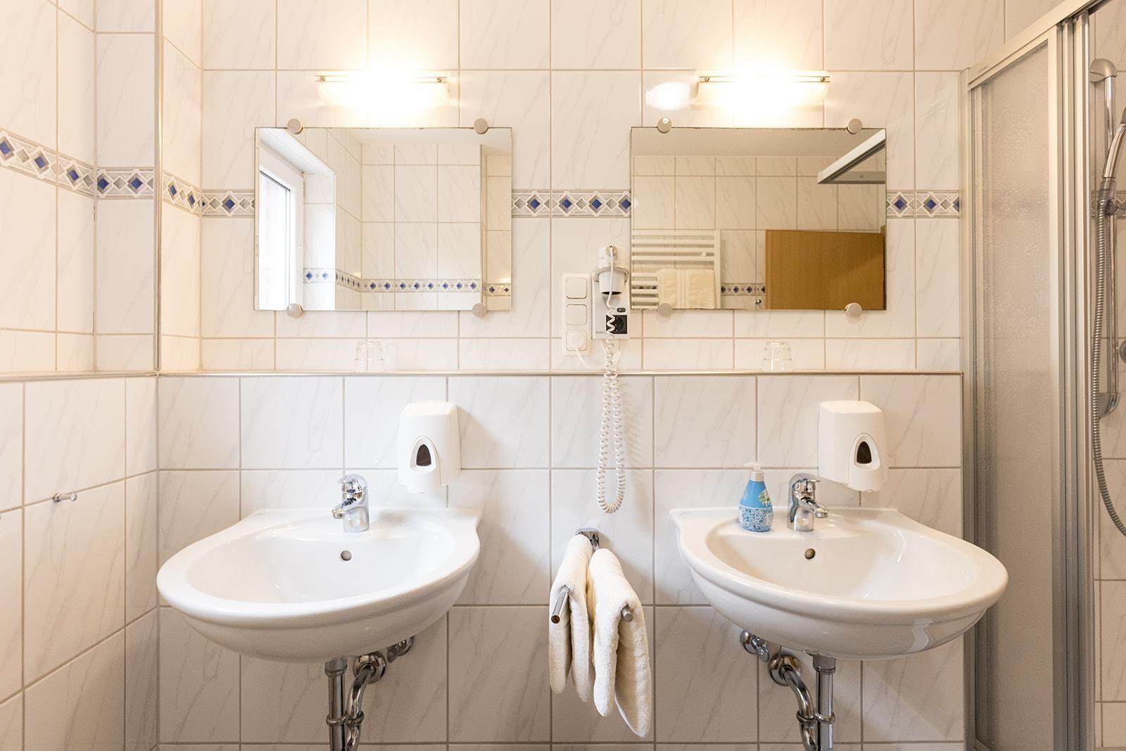 Two sinks with mirrors and shower area
