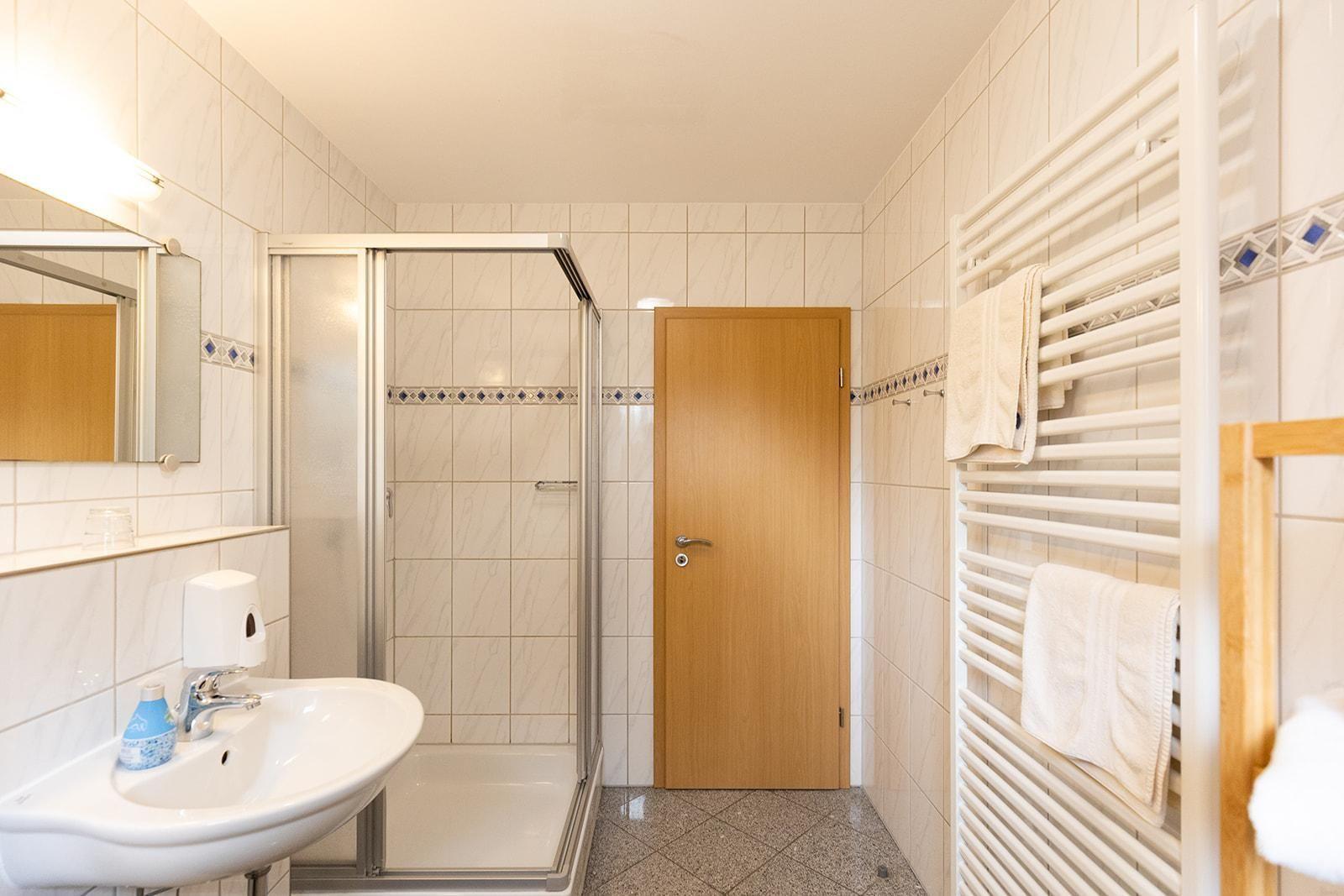 Bathroom with shower, sink, and towel rack.