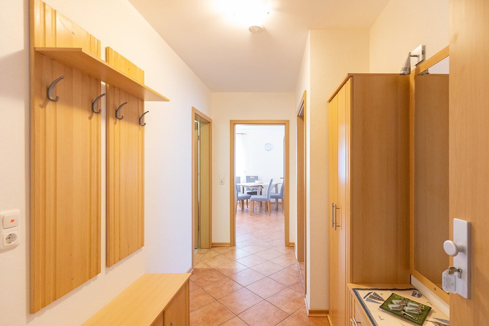 Hallway with coat rack, wardrobe, and view into dining room.