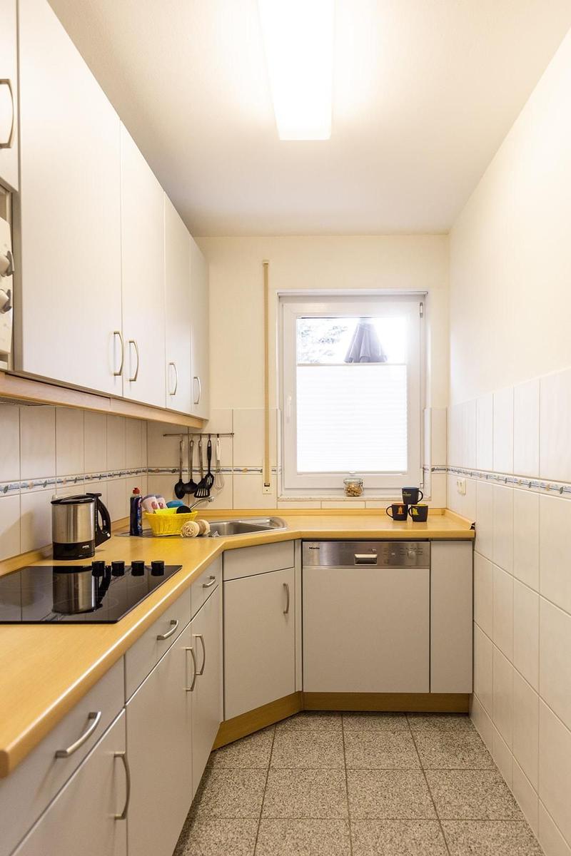 Kitchen with white cabinets, wooden countertop, and dishwasher