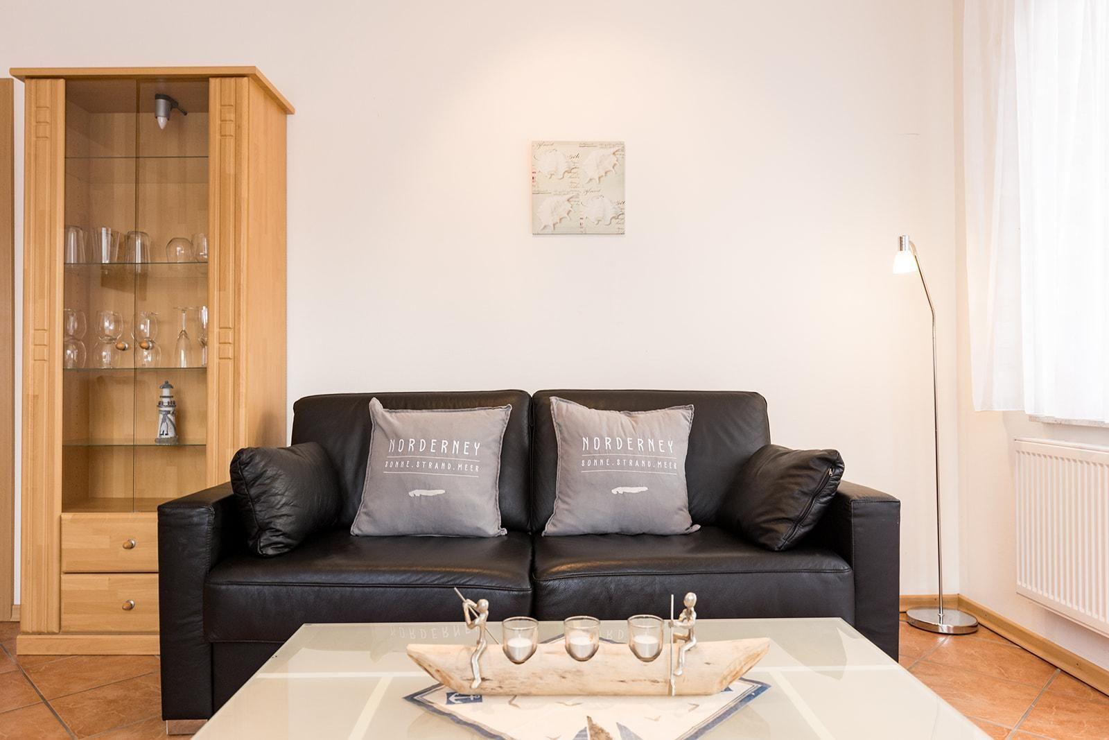 Black sofa with cushions, glass cabinet, and table with boat dish.
