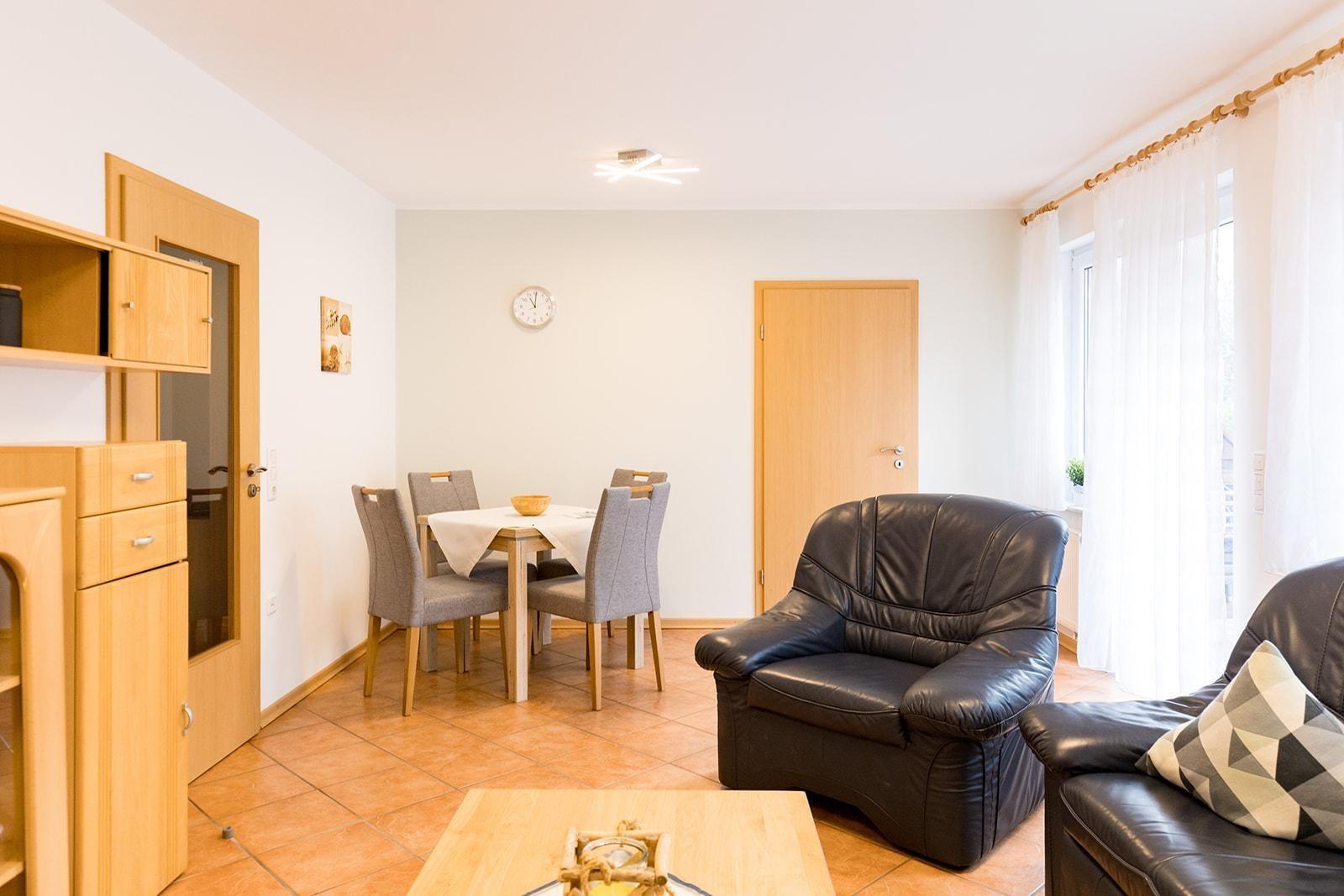 Wohn- und Essbereich mit Ledersofa, Tisch und Stühlen sowie Holzmöbeln.