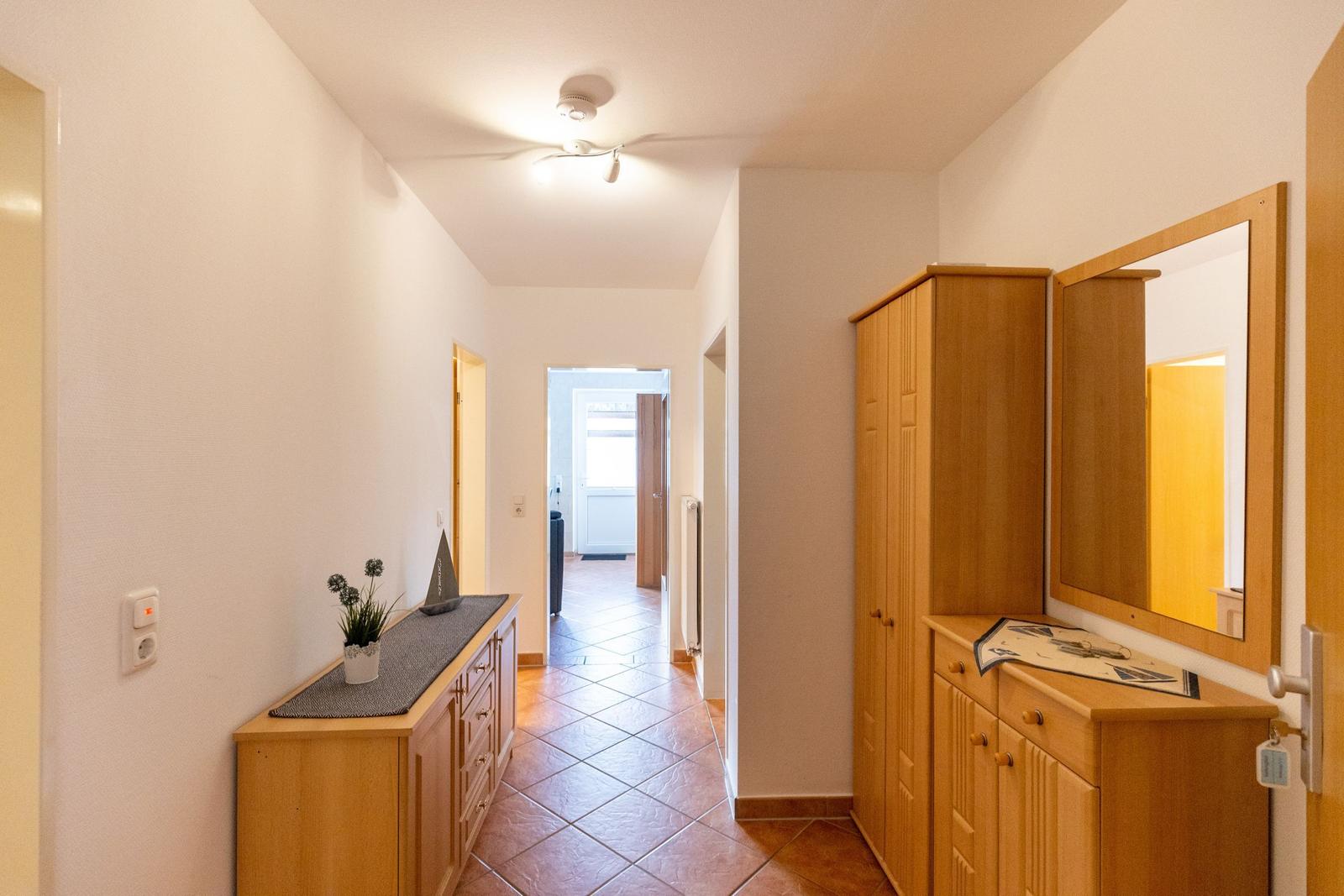 Flur mit Holzschrank, Spiegel und Schminktisch. Terrakottafliesen und Deckenventilator.