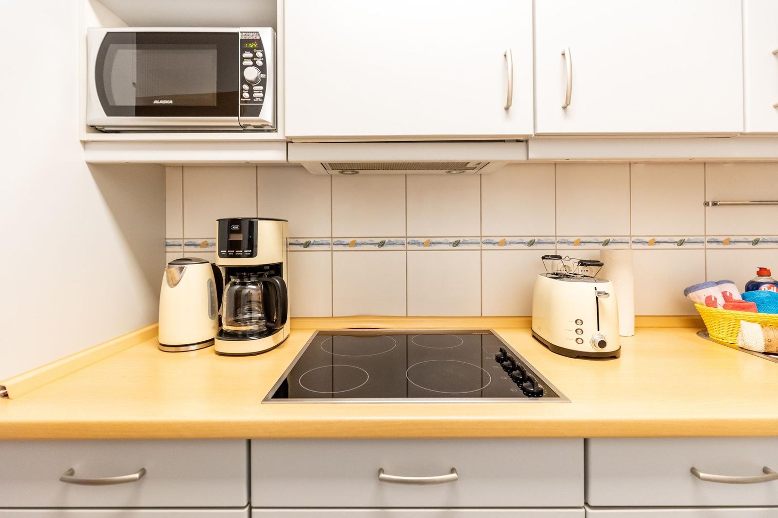 Küche mit Herd, Kaffeemaschine, Toaster und Mikrowelle.