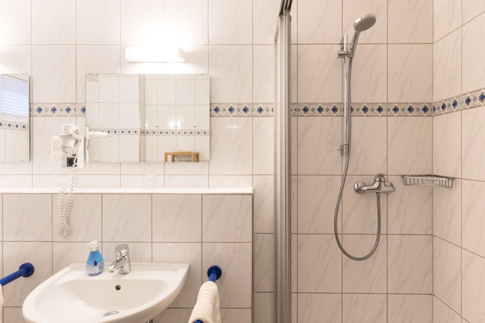Badezimmer mit Dusche, Waschbecken und Spiegel