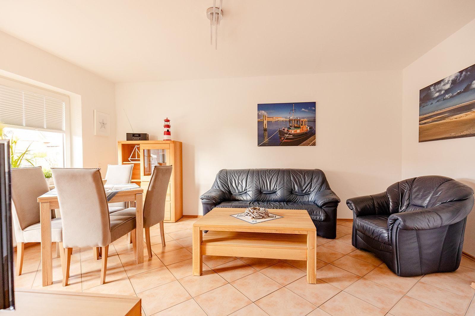 Wohn- und Essbereich mit Ledersofa, Esstisch und Wandbildern.