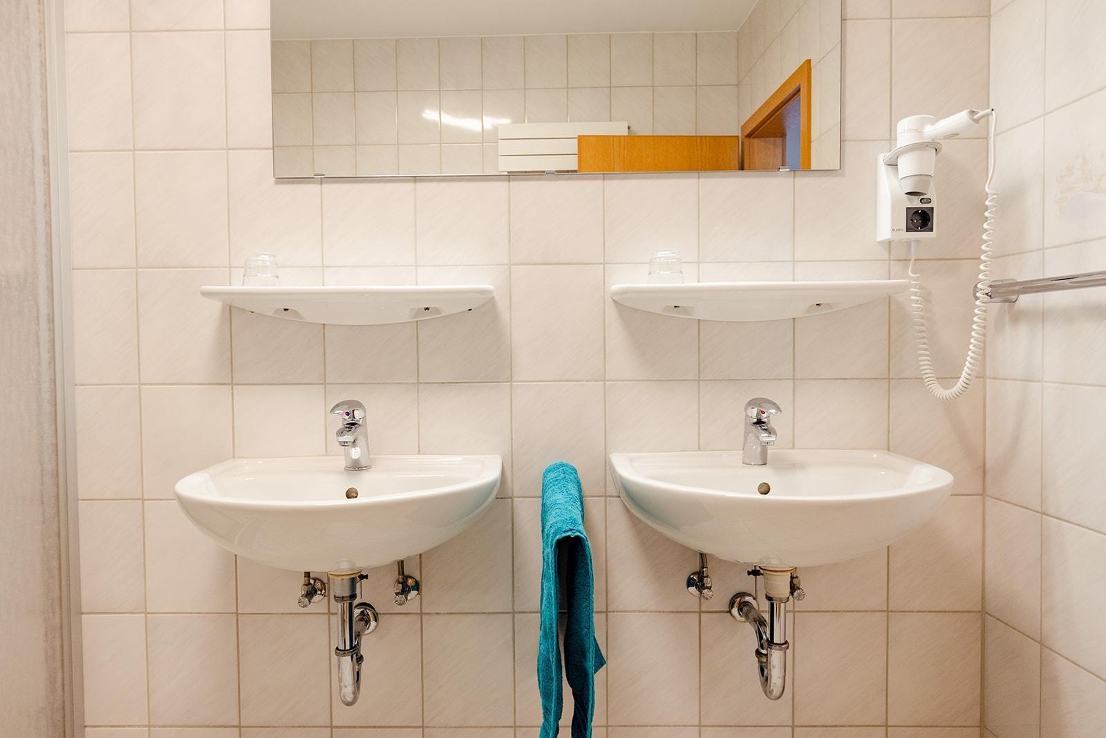 Zwei Waschbecken mit Spiegeln und Handtuchhalter an der Wand.
