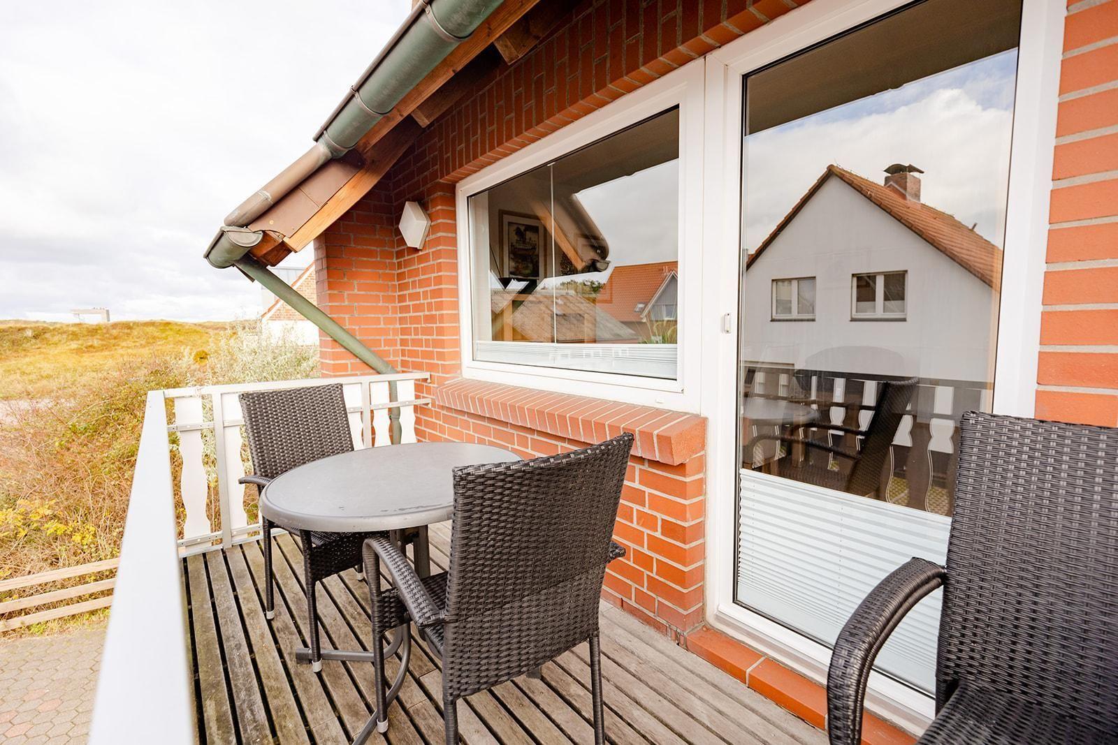 Terrasse mit Tisch und Stühlen, Blick auf Grünland und Haus.