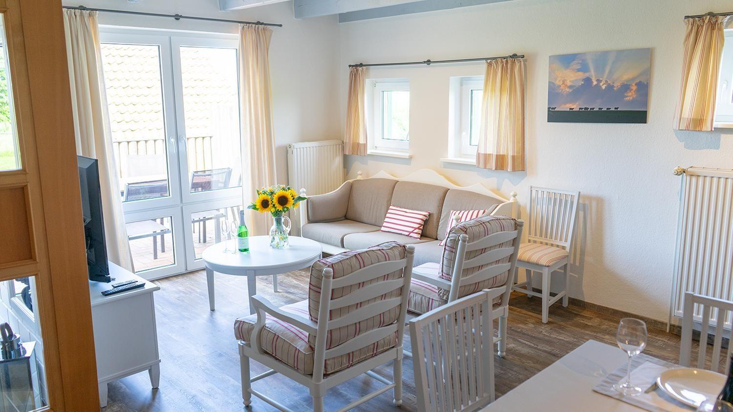 Wohnzimmer mit Sofa, Stühlen, Tisch und Blick auf Balkon.