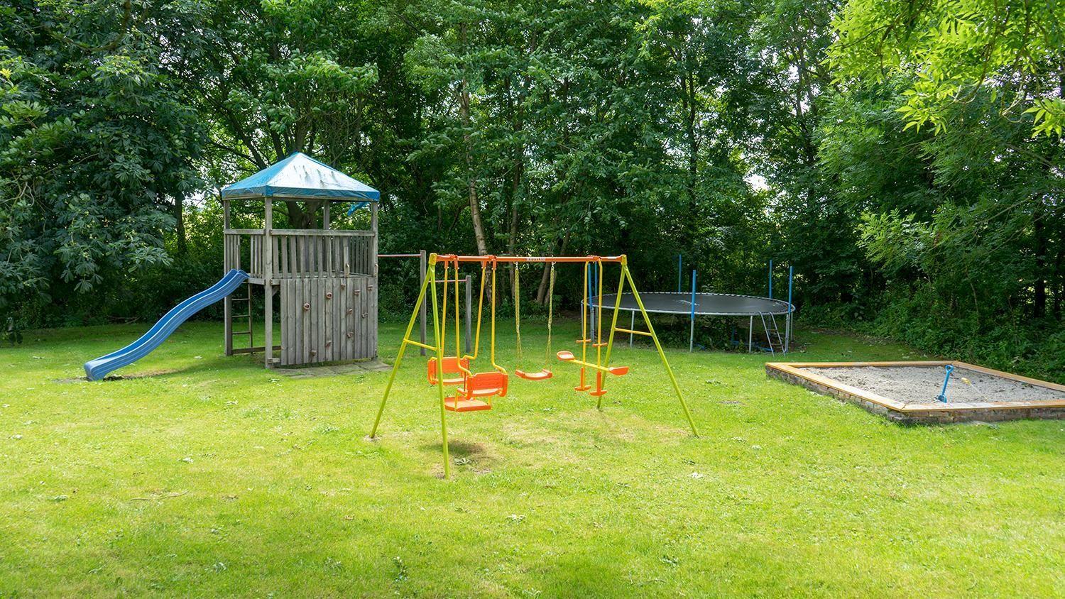 Large garden with playground, swings, sandbox, and trampoline.