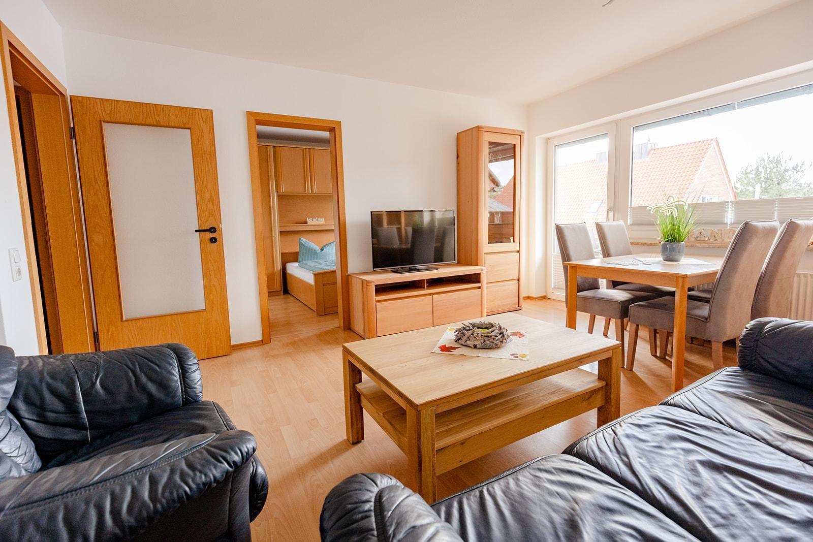 Wohnzimmer mit Essbereich, TV und Blick auf die Straße.