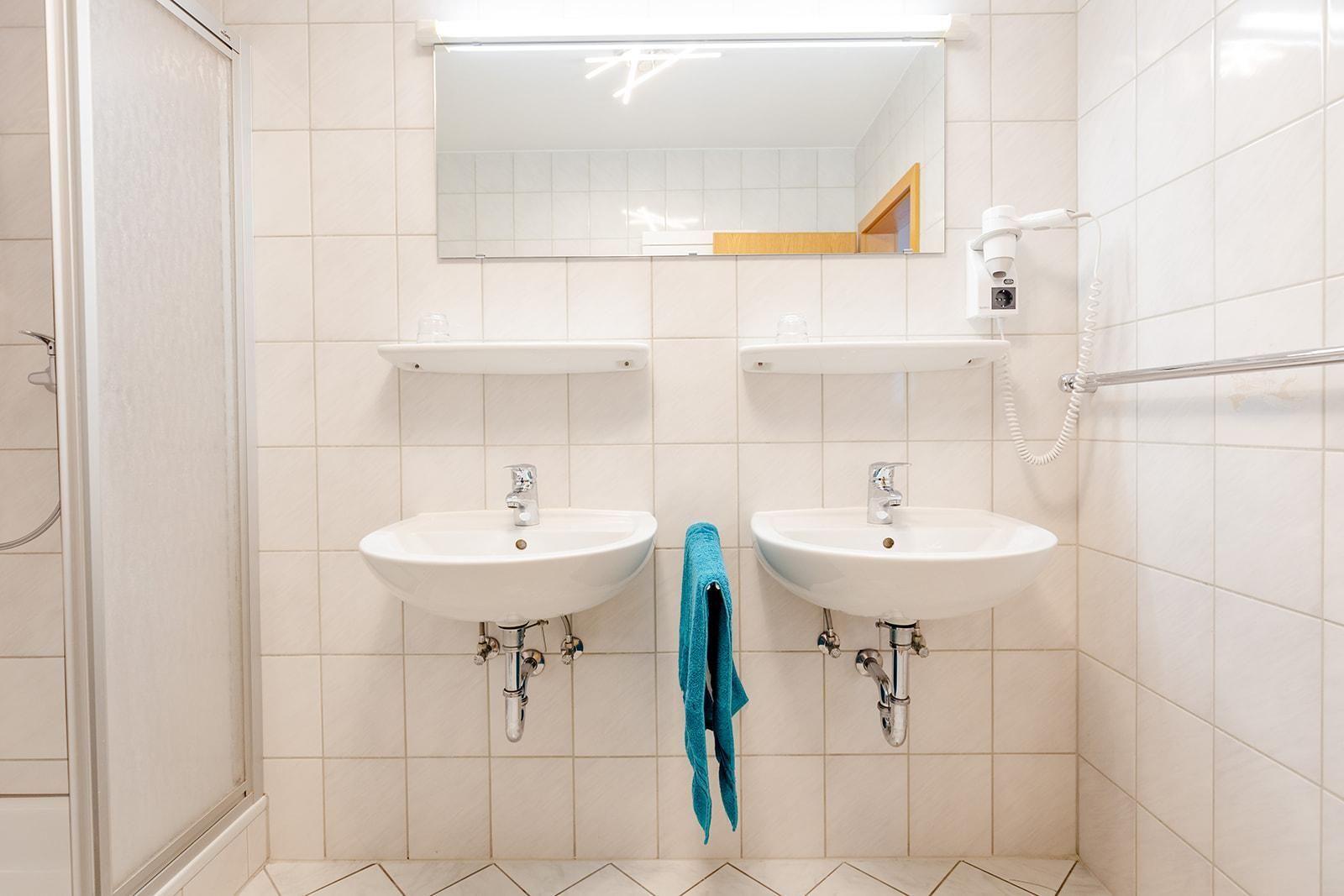 Zwei Waschbecken mit Spiegeln und Handtuchhalter an der Wand