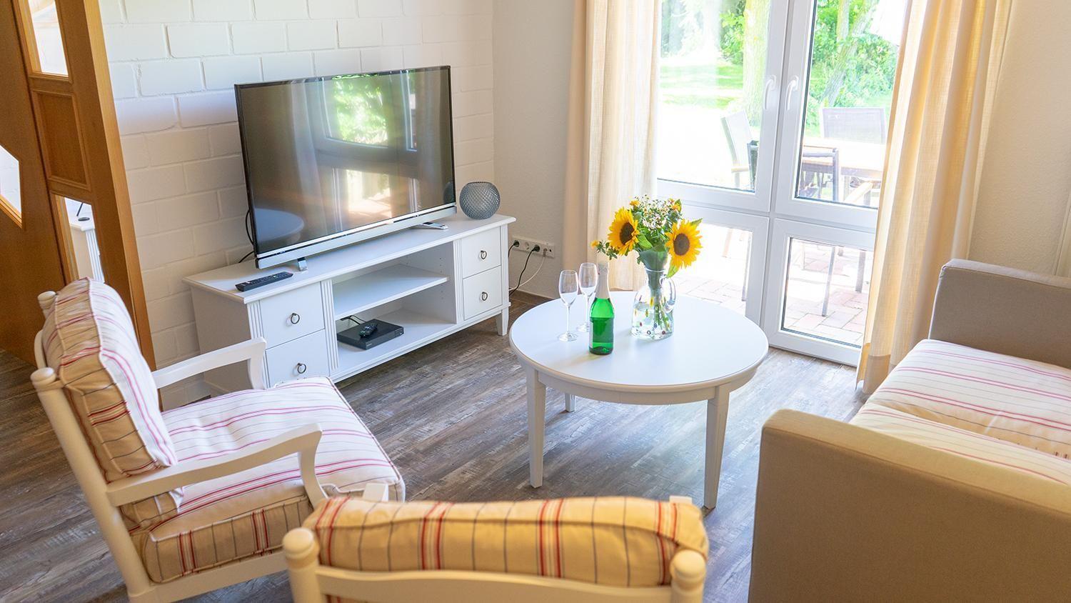 Wohnzimmer mit TV, Couch, Tisch und Blick auf die Terrasse.