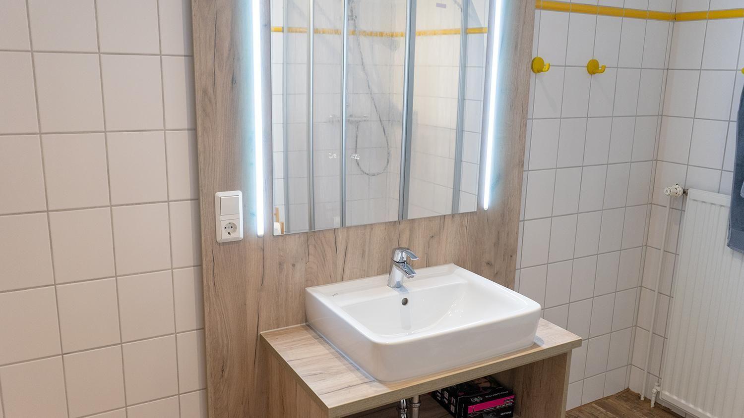 Badezimmer mit Waschbecken, Spiegel und Dusche
