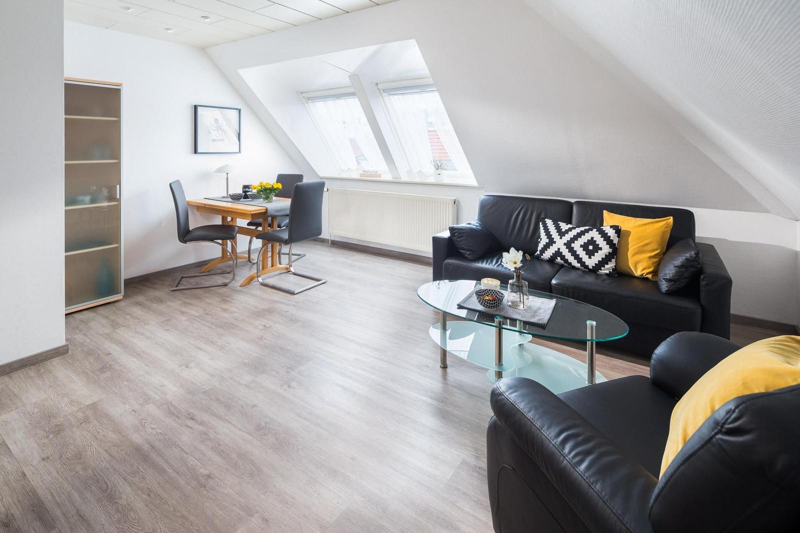 Wohn- und Essbereich mit Sofa, Stühlen und Dachfenstern.