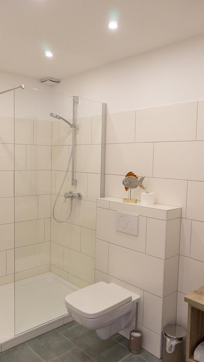 Badezimmer mit Dusche, Toilette und Fischdekoration