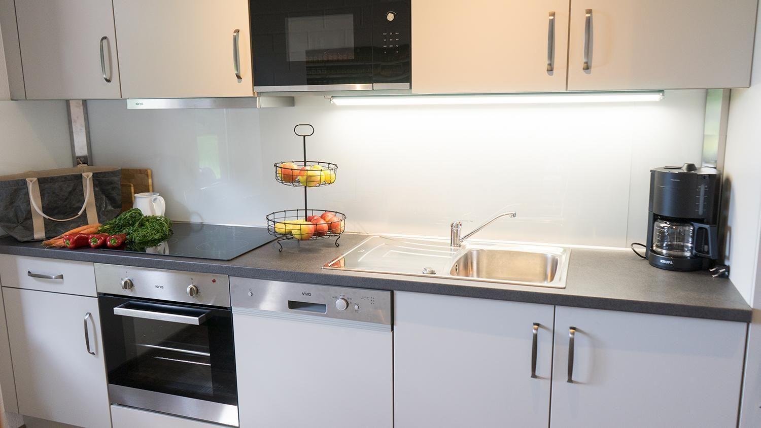 Küche mit Arbeitsfläche, Spüle, Kühlschrank und Kochfeld.