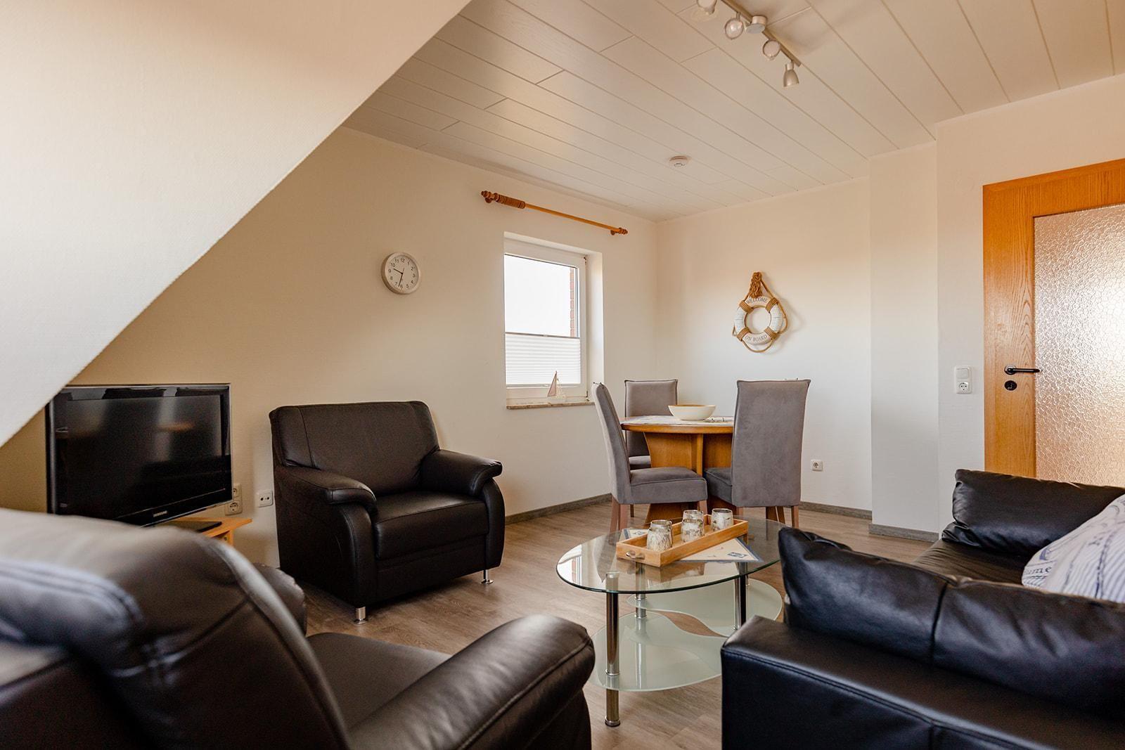 Wohn- und Essbereich mit Ledersofa, Sessel und Glas-Tisch.
