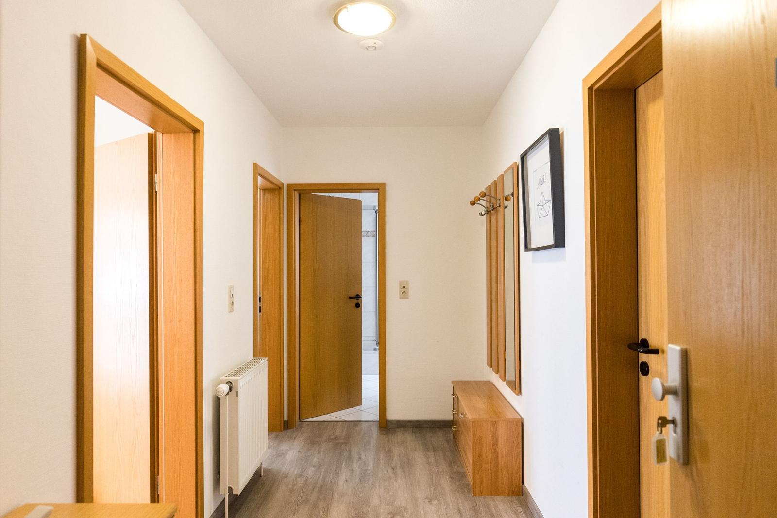 Flur mit Holztüren, Heizkörper und Kleiderhaken an der Wand.