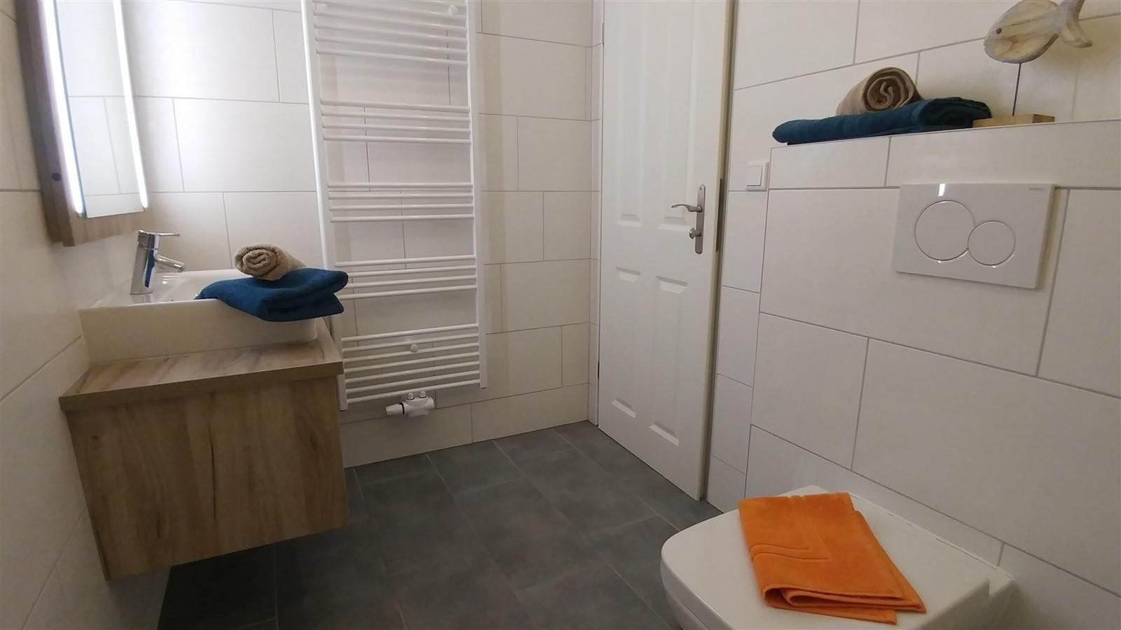 Badezimmer mit Waschbecken, Toilette und Heizkörper