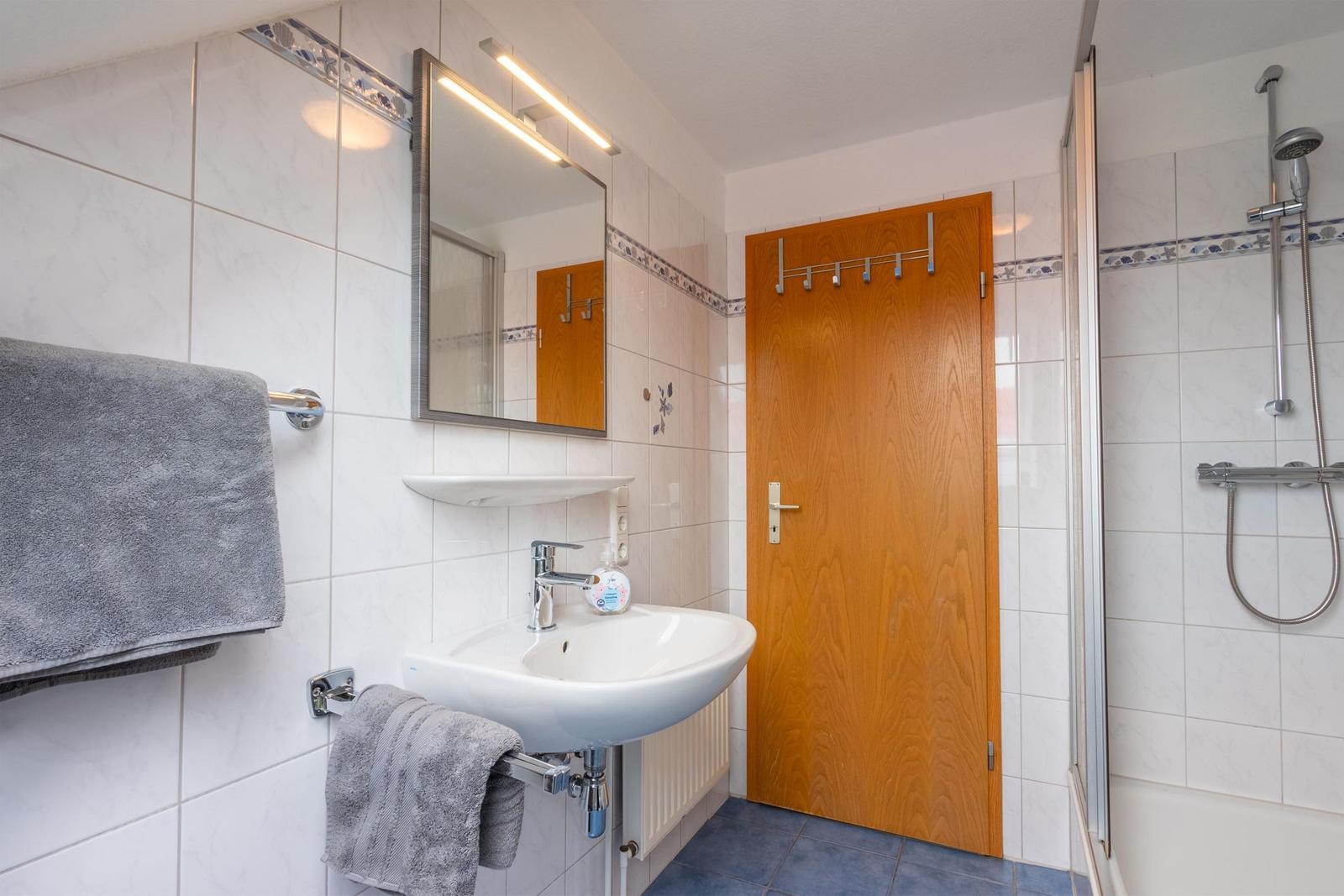 Badezimmer mit Dusche, Waschbecken und Spiegel