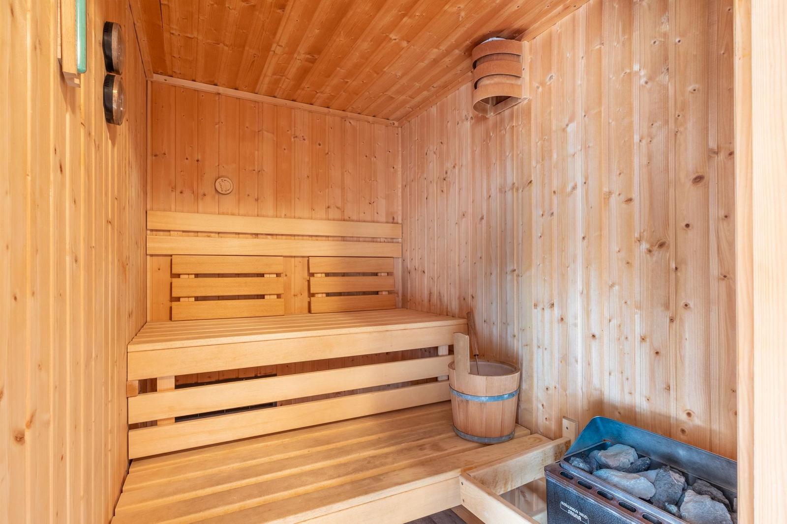 Holzsauna mit Sitzbank, Eimer und Steinkiste