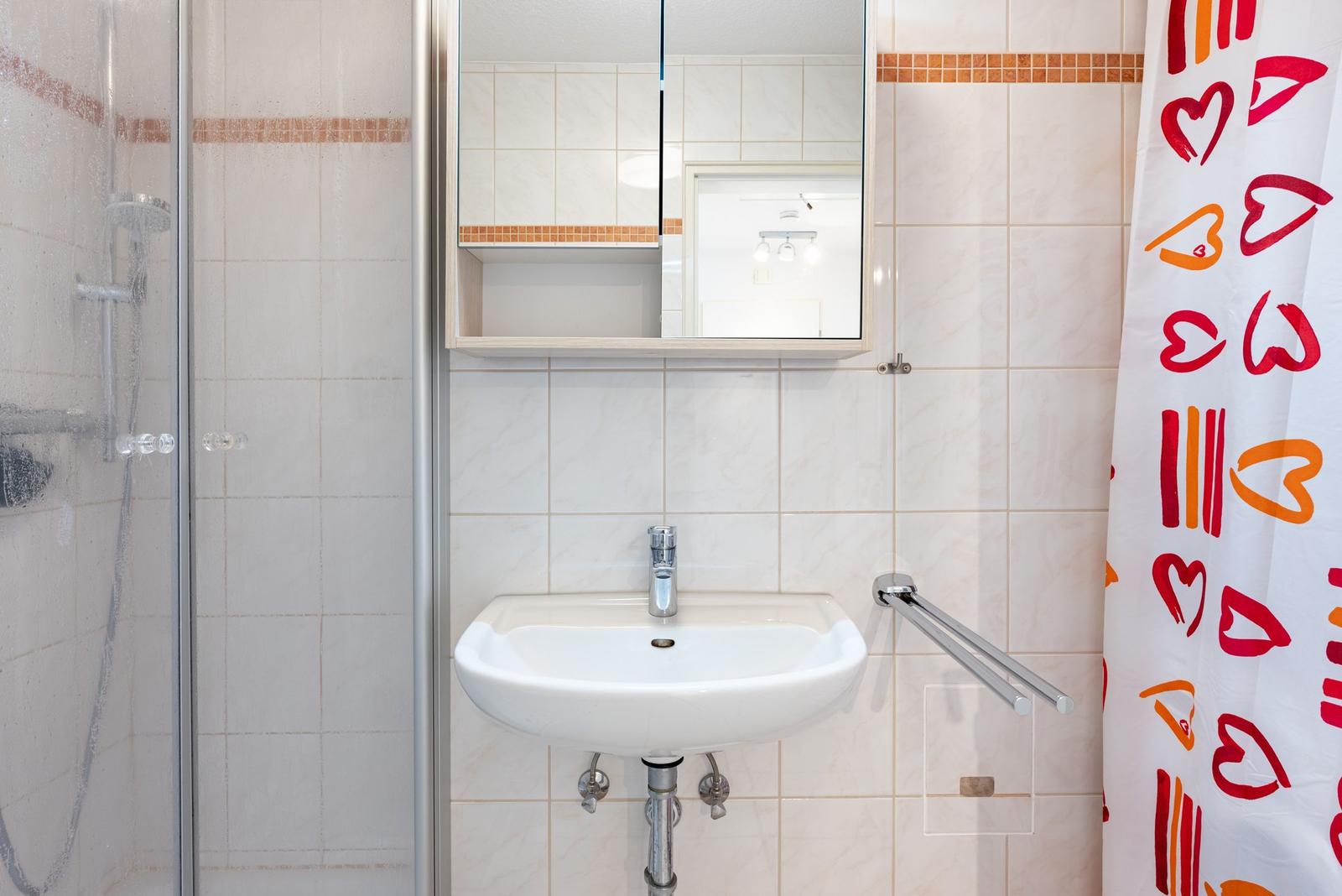 Bad mit Dusche, Waschbecken und Spiegel