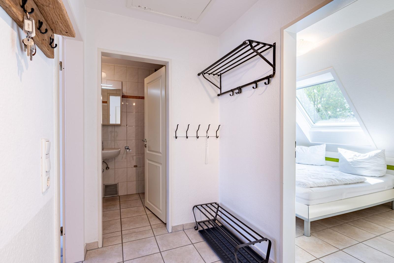 Flur mit Schlafzimmer und Bad. Haken und Handtuchhalter an der Wand.