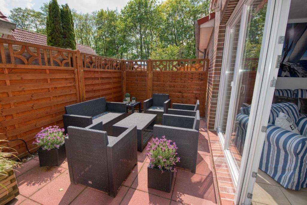 Terrasse mit Sitzgruppe, Pflanzen und Holzgeländer. Durchgang zur Wohnung mit Sofa.
