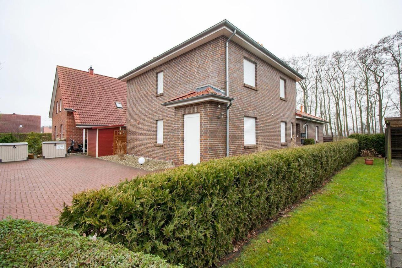 Zweistöckiges Haus mit Garten und Terrasse. Roter Dachfirst und Ziegelmauer.