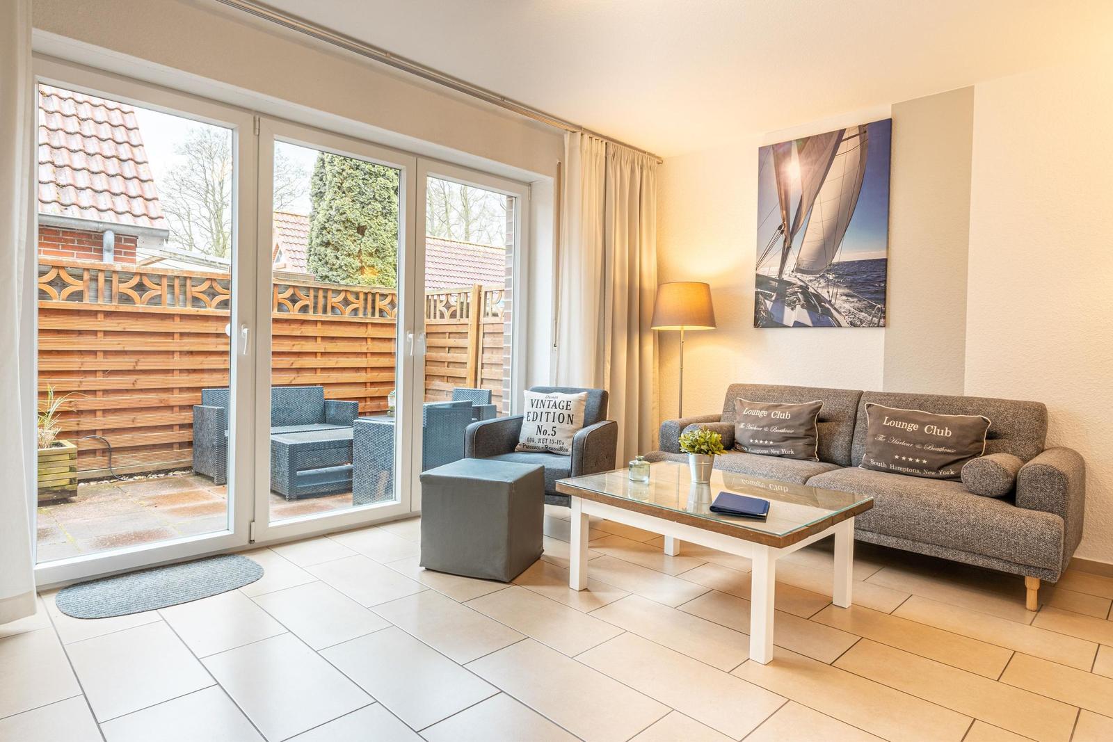 Wohnzimmer mit Sofa, Couchtisch und Terrasse mit Gartenmöbeln.