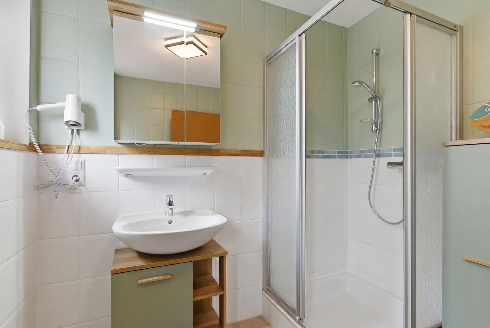 Badezimmer mit Dusche, Waschbecken und Spiegel