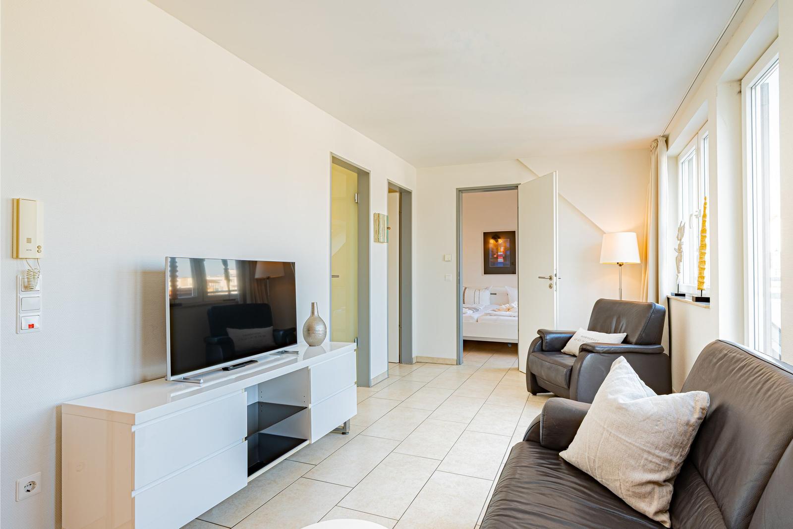 Wohnbereich mit Sofa, Fernseher und Blick in Schlafzimmer