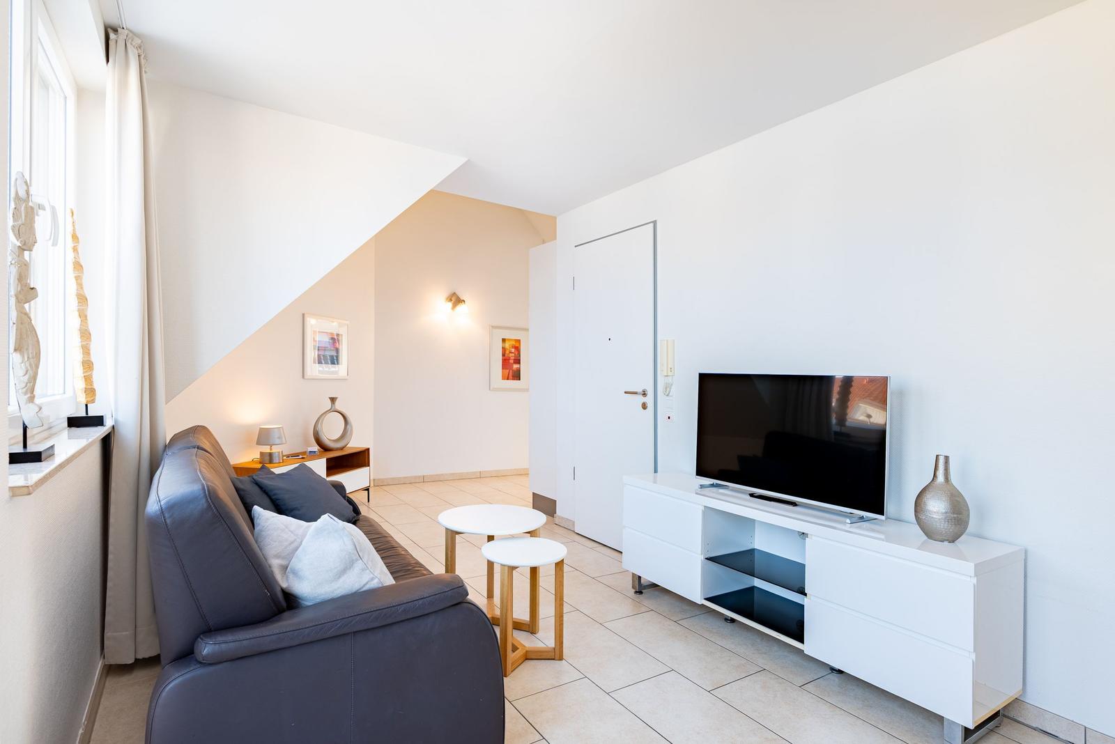 Wohnzimmer mit Sofa, Fernseher und Tischen