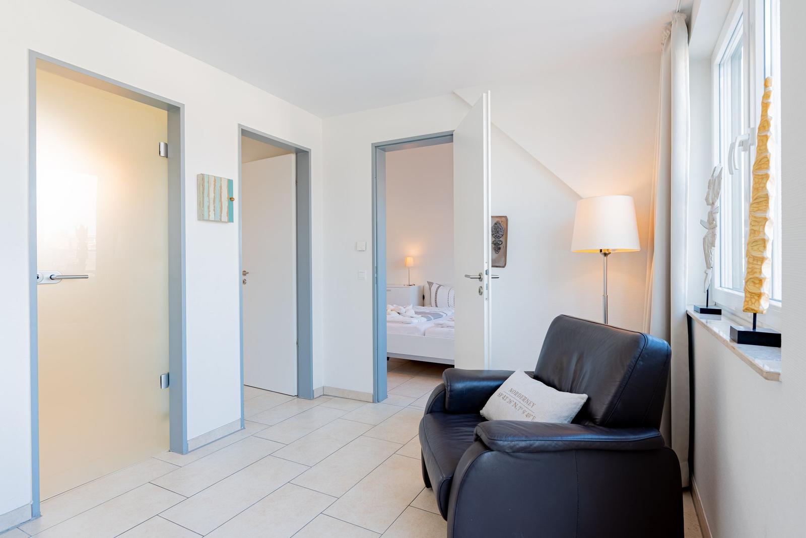 Flur mit Sitzgelegenheit, Blick in Schlafzimmer und Türen zu weiteren Räumen.